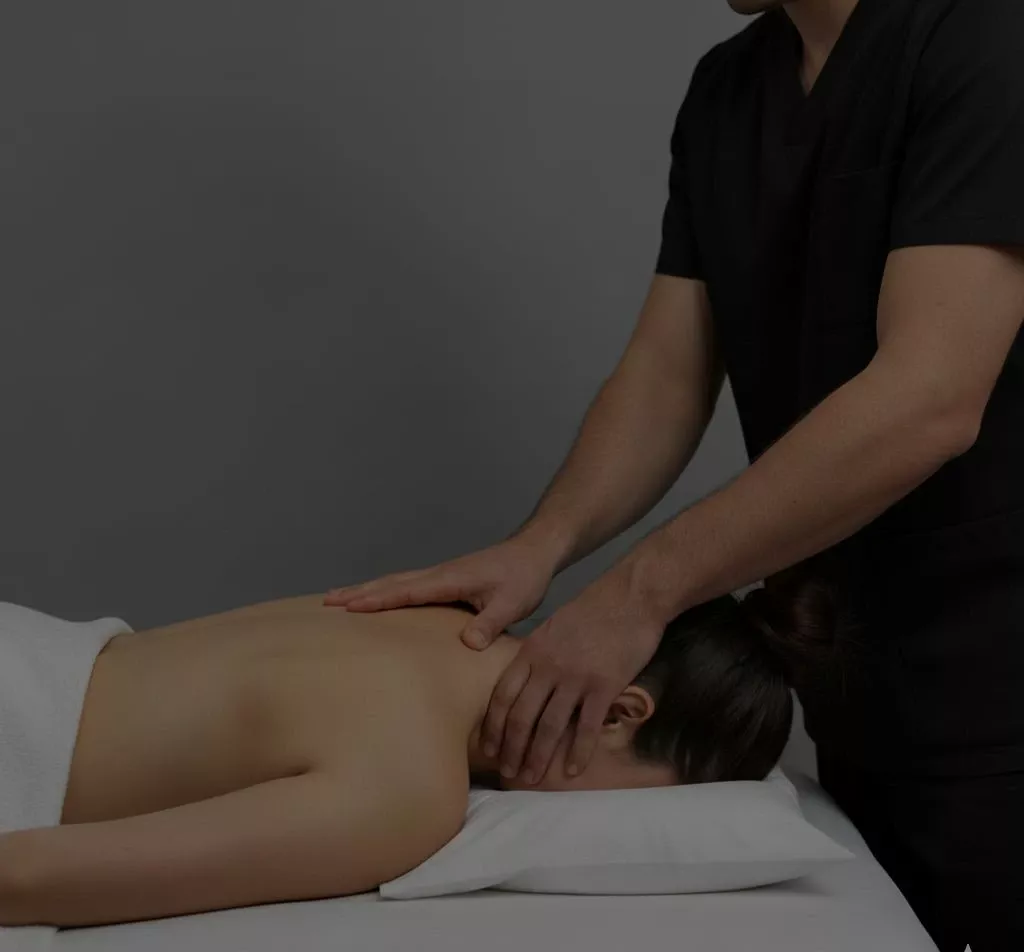 Масажист робить масаж шиї та комірцевої зони